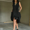 A woman wearing a sleeveless black dress with a sporty, utilitarian design. The dress includes a hood, a front zipper closure, and drawstring details at the waist and hem, allowing for adjustable ruching. The silhouette is voluminous and sculptural, particularly around the hemline, which forms a balloon-like shape, chunky black platform sandals. The background is plain white.