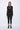 Woman wearing a black outfit with sheer sleeves on a white background