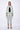 Woman wearing a light green outfit with a jacket and pants on a white background