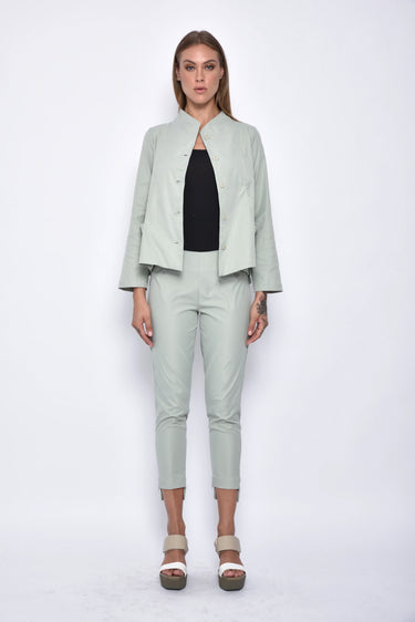 Woman wearing a light green outfit with a jacket and pants on a white background
