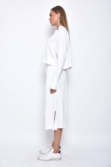 A female model wearing a white long sleeve top and white cropped pants, with white background