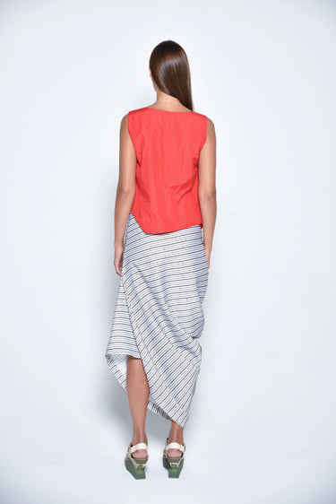 A female model wearing a Red sleeveless top, uneven hem, Black horizontal striped asymmetrical skirt and sandals against a white background