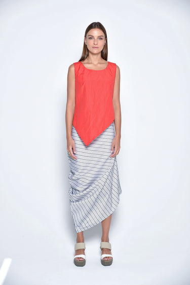 A female model wearing a Red sleeveless top, uneven hem, Black horizontal striped asymmetrical skirt and sandals against a white background