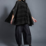 Woman modeling a black knit poncho, wide-leg pants and boots against gray backdrop, Simply Mila modern women's clothing