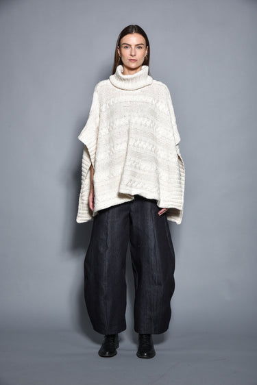 Woman modeling modern cream knit turtleneck poncho and wide-leg black pants, Simply Mila fashion