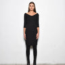Woman wearing a black dress with scoop neckline against a white background